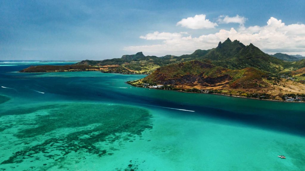 Aerial view of a coastal area with clear turquoise water and rugged mountain landscape, symbolizing tax consulting clarity.